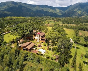 Una casa grande rodeada de exuberante vegetación y montañas.