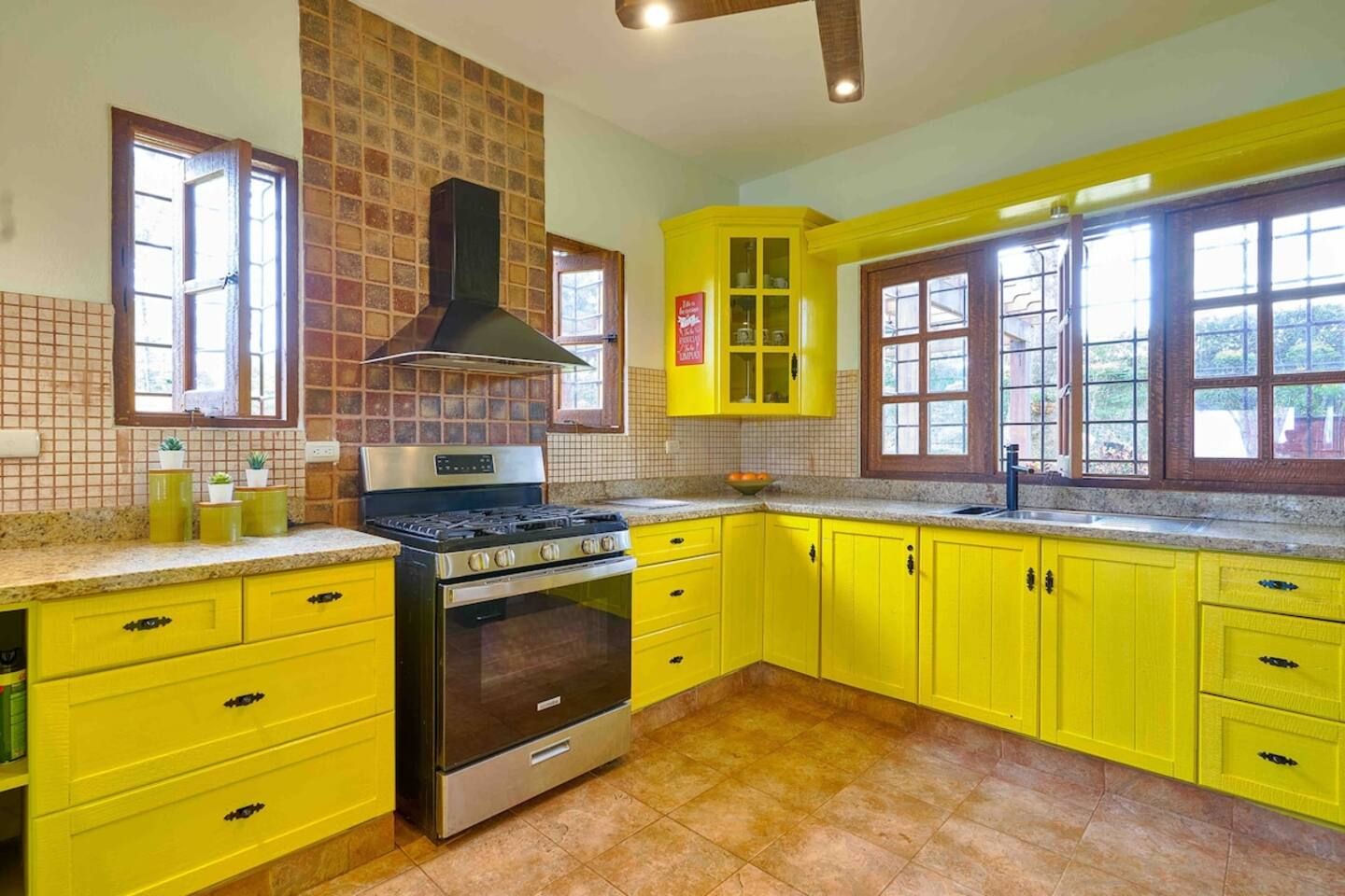 Uma cozinha com armários amarelos, fogão e painel de azulejos.