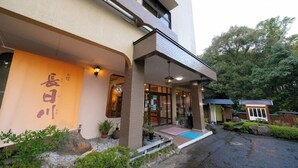 A building with a covered entrance, potted plants, and a small outdoor seating area. - Nagahigawa (Miyazaki)
