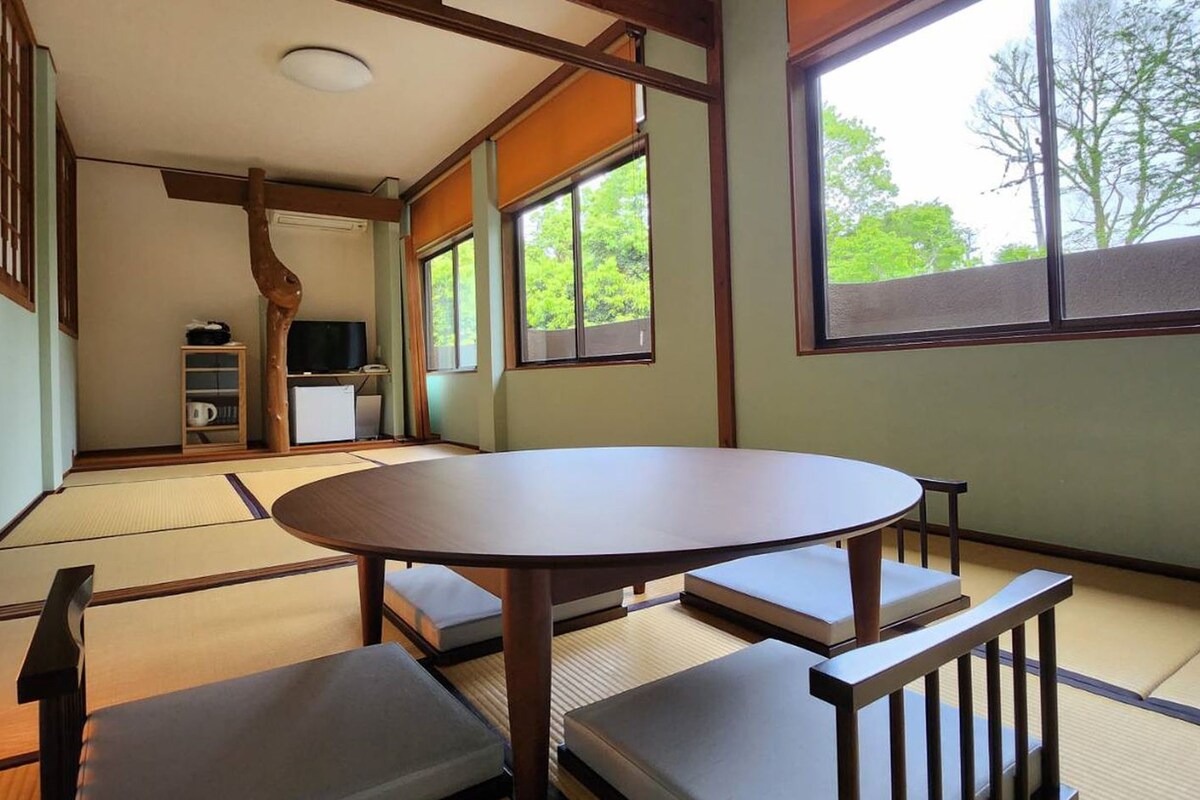 A traditional Japanese room with tatami flooring, a low table with cushions, and a sliding door.