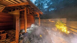 A wooden structure with a stone floor, a wooden fence, and a small plant. - Nagahigawa (Miyazaki)