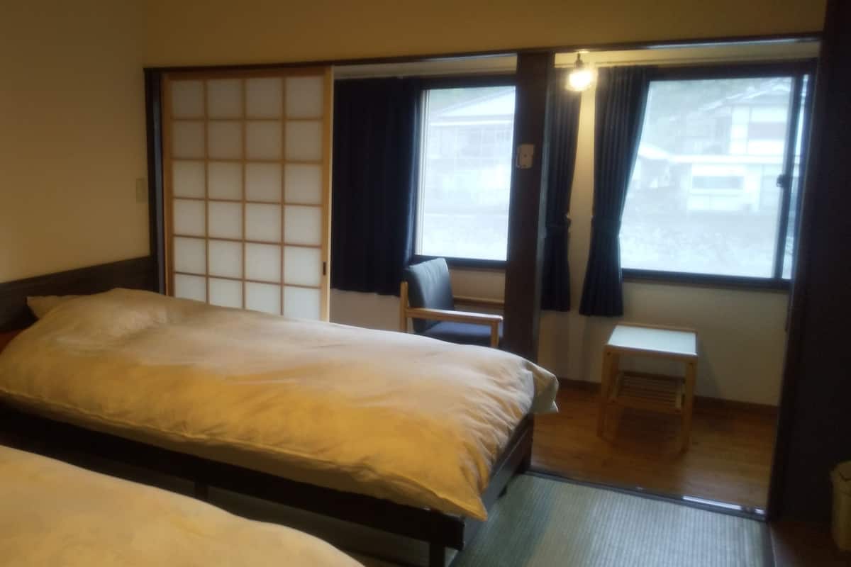 A room with two beds, a sliding shoji screen, a chair, and a small table.