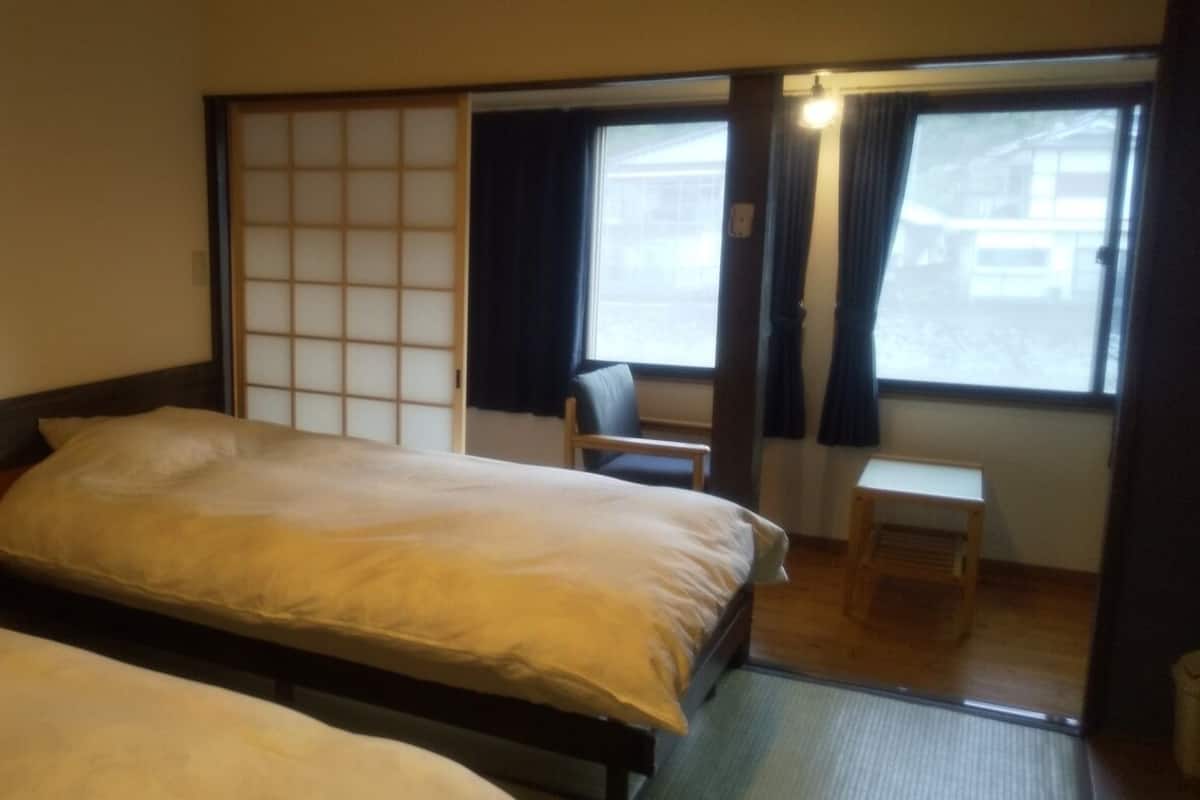 A room with two beds, a sliding shoji screen, a chair, and a small table.