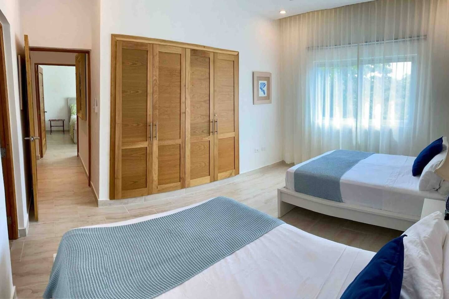 A bedroom with two beds, a wardrobe, and a view of the outdoors.