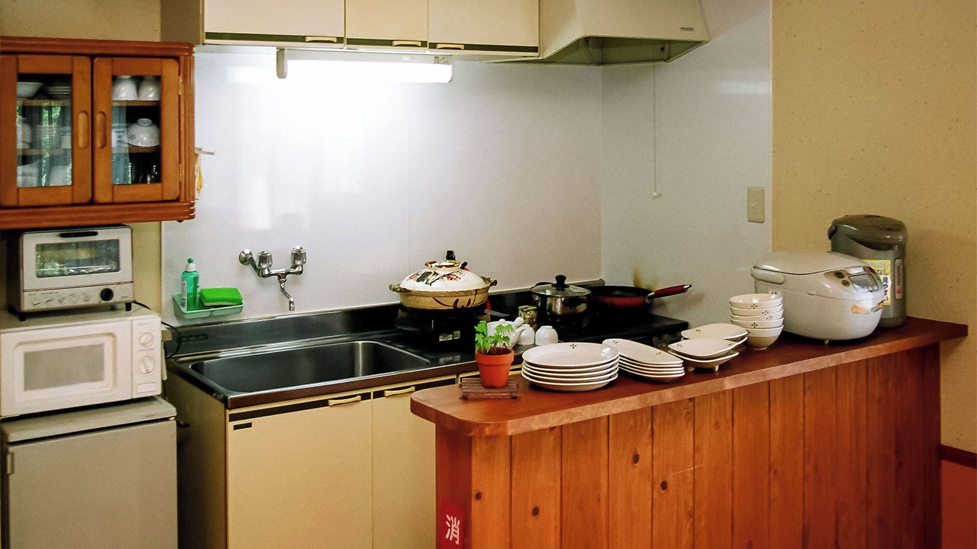 A compact kitchen with a microwave, stove, sink, and wooden cabinets.