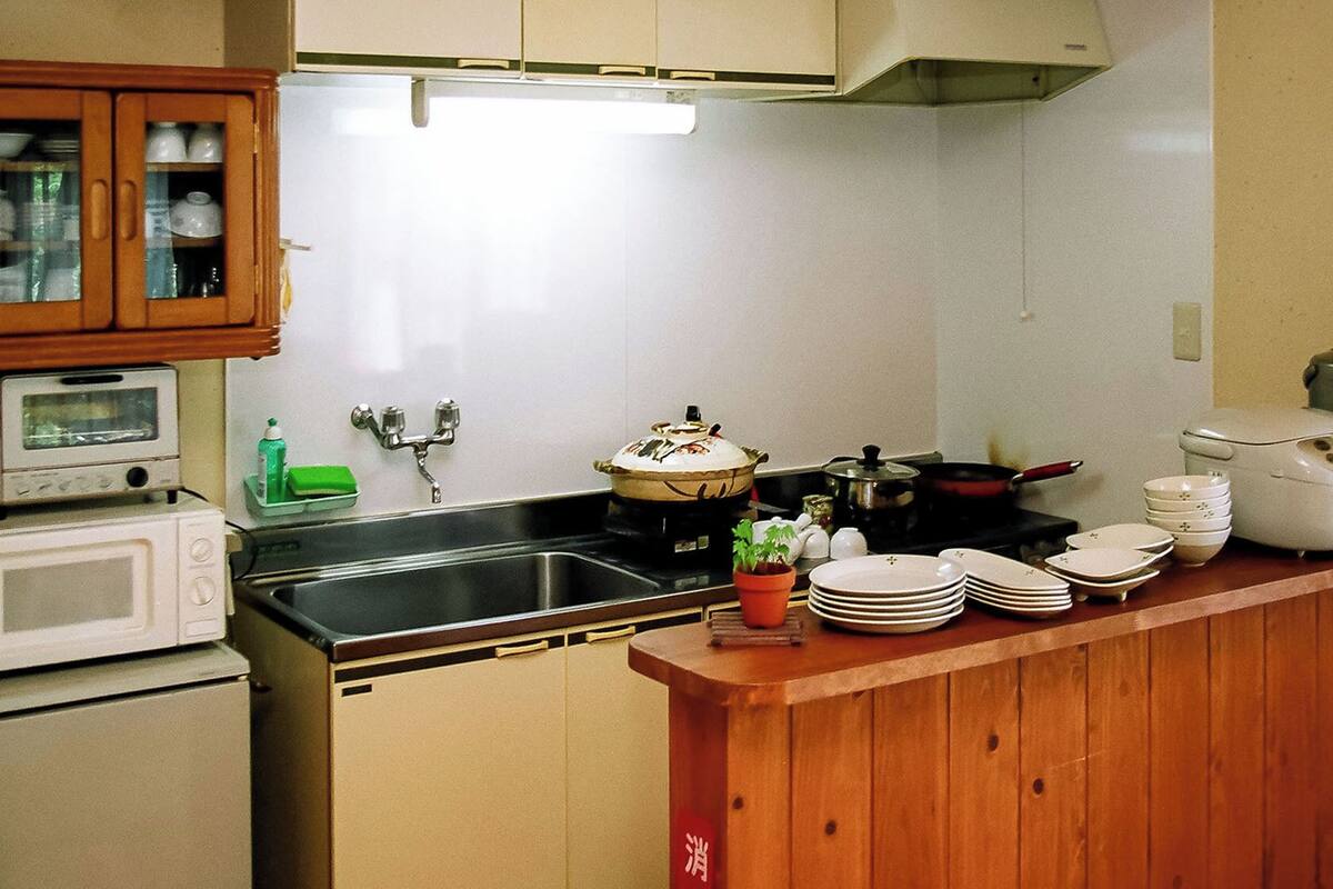 A compact kitchen with a microwave, stove, sink, and wooden cabinets.