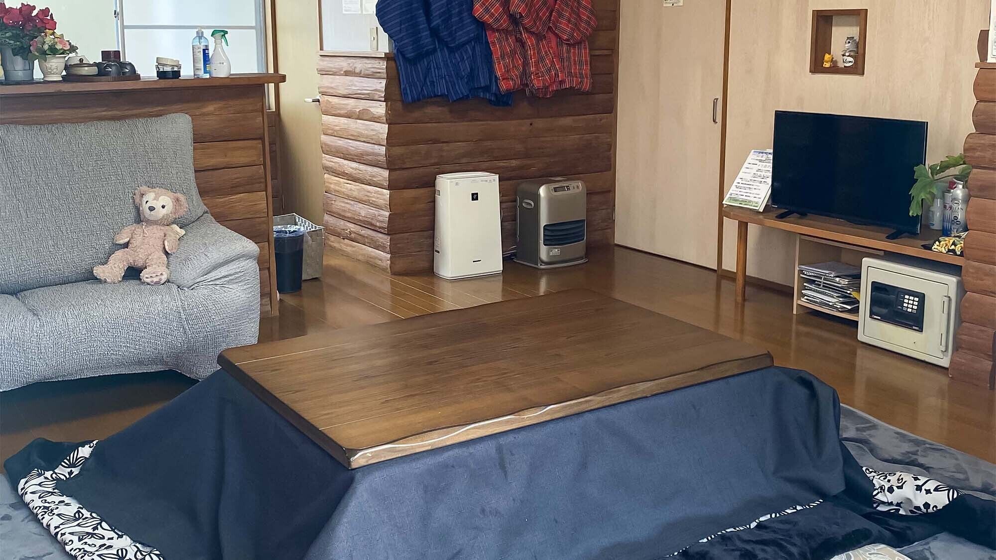 A living room with a sofa, a small table, a TV, a microwave, and a heater.