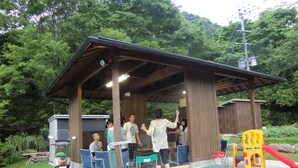 A covered outdoor area with a wooden structure, seating, and a play area with a slide. - Yufuin Onsen Cottage Kohan (Yufu)