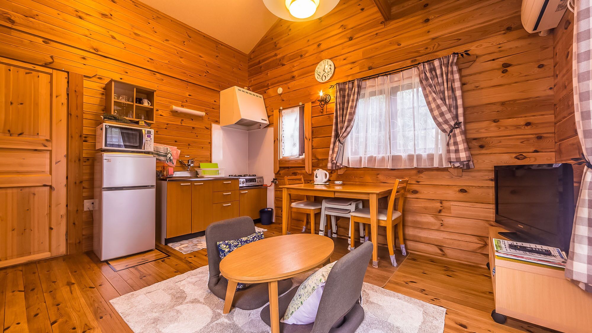 Interior acogedor de una cabaña con cocina, comedor y televisor.