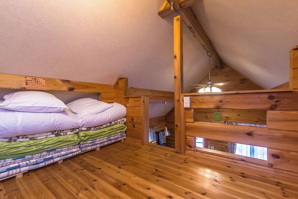 A wooden cabin room with a bunk bed, a wooden ceiling, and a small window.