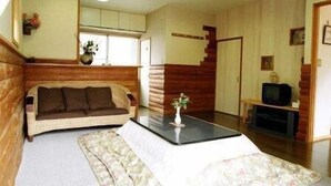 A living room with a sofa, a coffee table, a TV, and a staircase. - Yufuin Onsen Cottage Kohan (Yufu)
