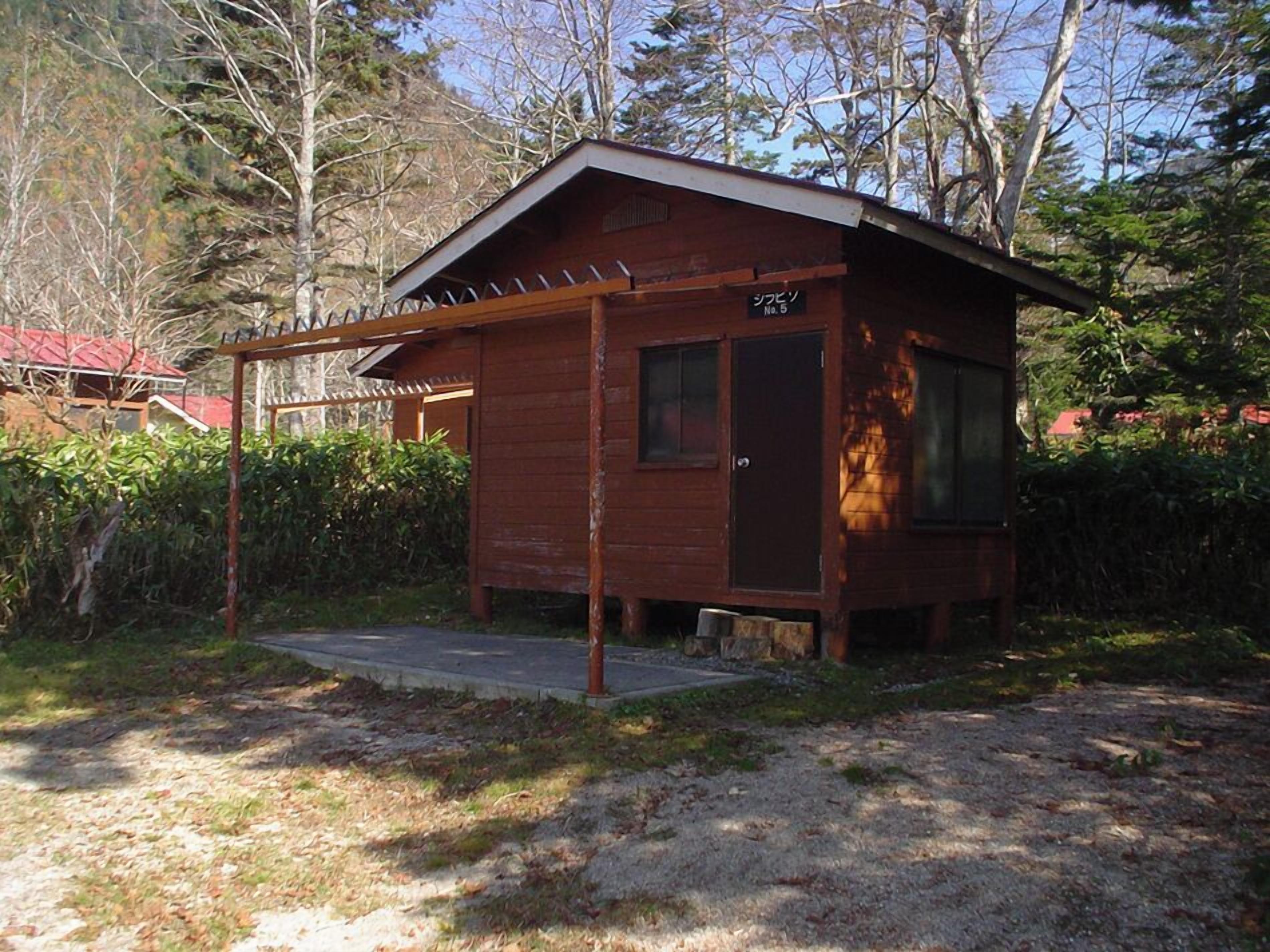 Een klein houten vakantiehuisje met een schuin dak, een deur en een raam.