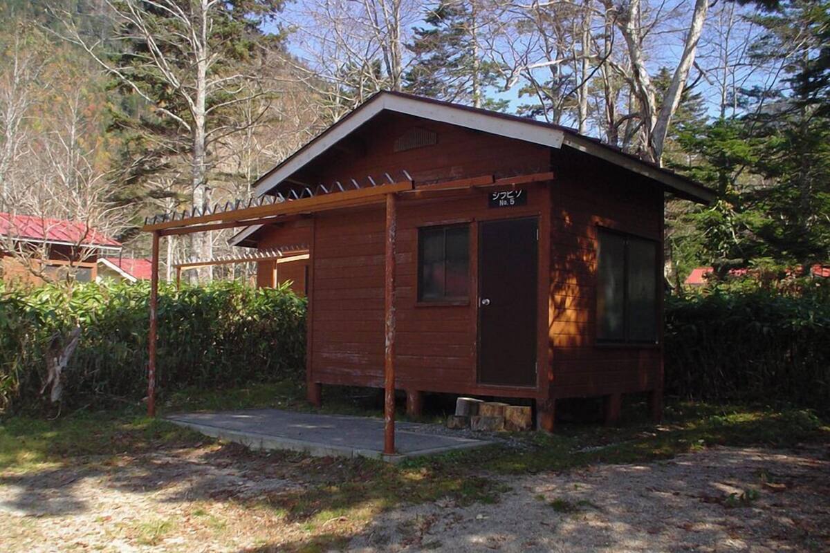 Een klein houten vakantiehuisje met een schuin dak, een deur en een raam.