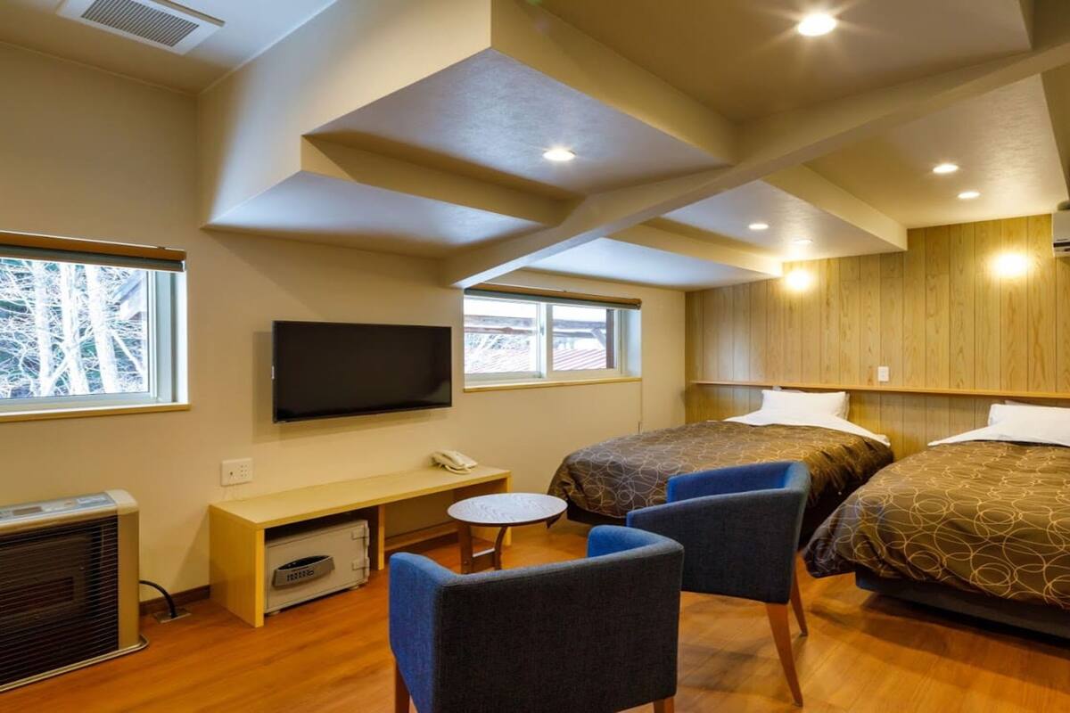 Une chambre d’hôtel avec deux lits, une télévision, un bureau et une chaise.
