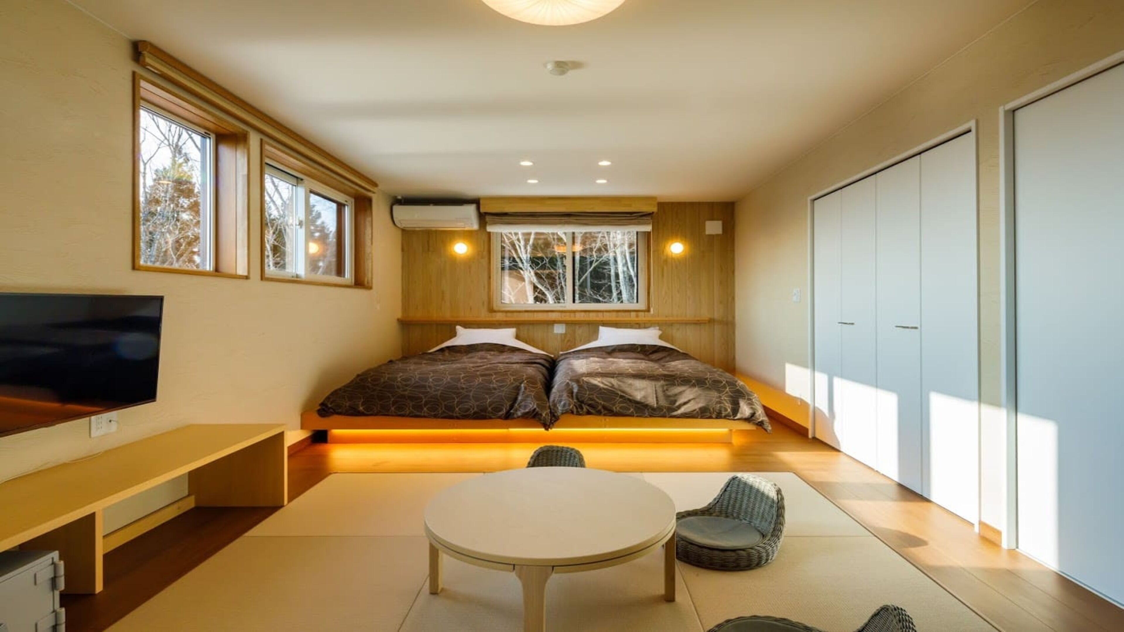 Una camera da letto moderna con un letto, una televisione, un tavolo da pranzo e un armadio.