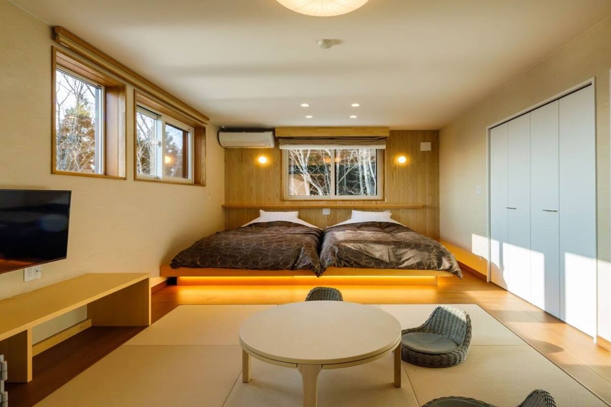 Une chambre à coucher moderne avec un lit, une télévision, une table à manger et une armoire.