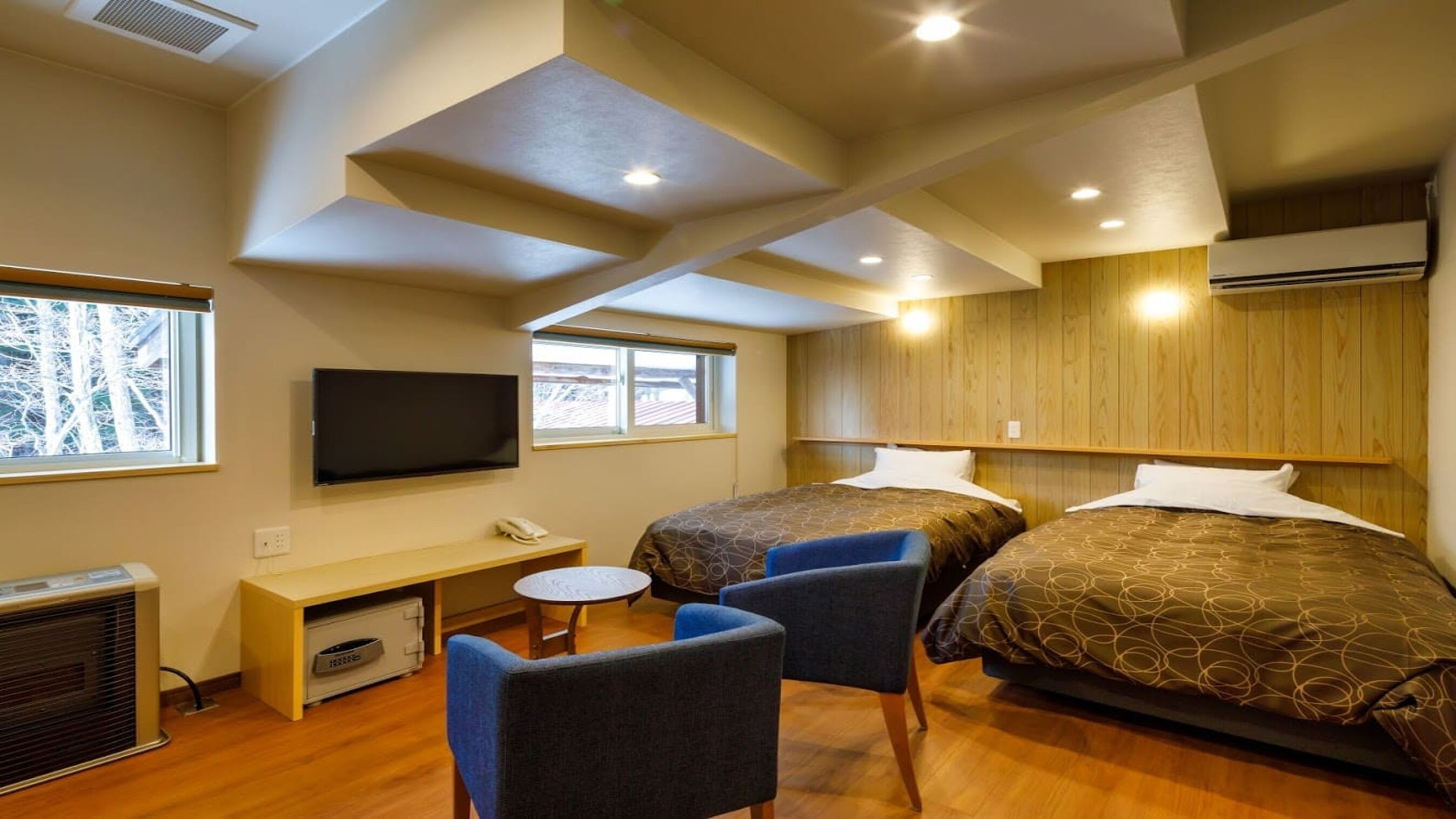A hotel room with two beds, a TV, a desk, and a chair.