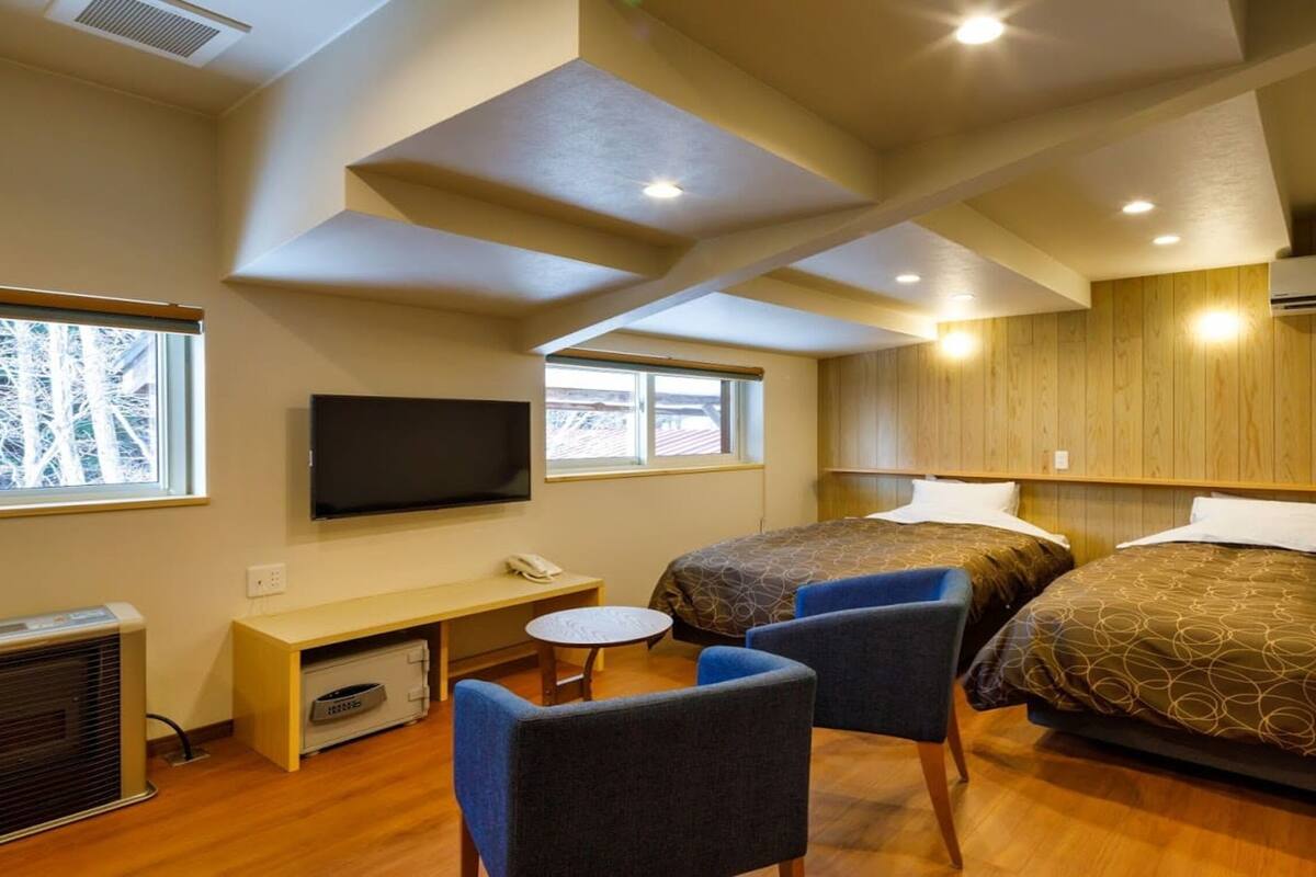 Une chambre d’hôtel avec deux lits, une télévision, un bureau et une chaise.