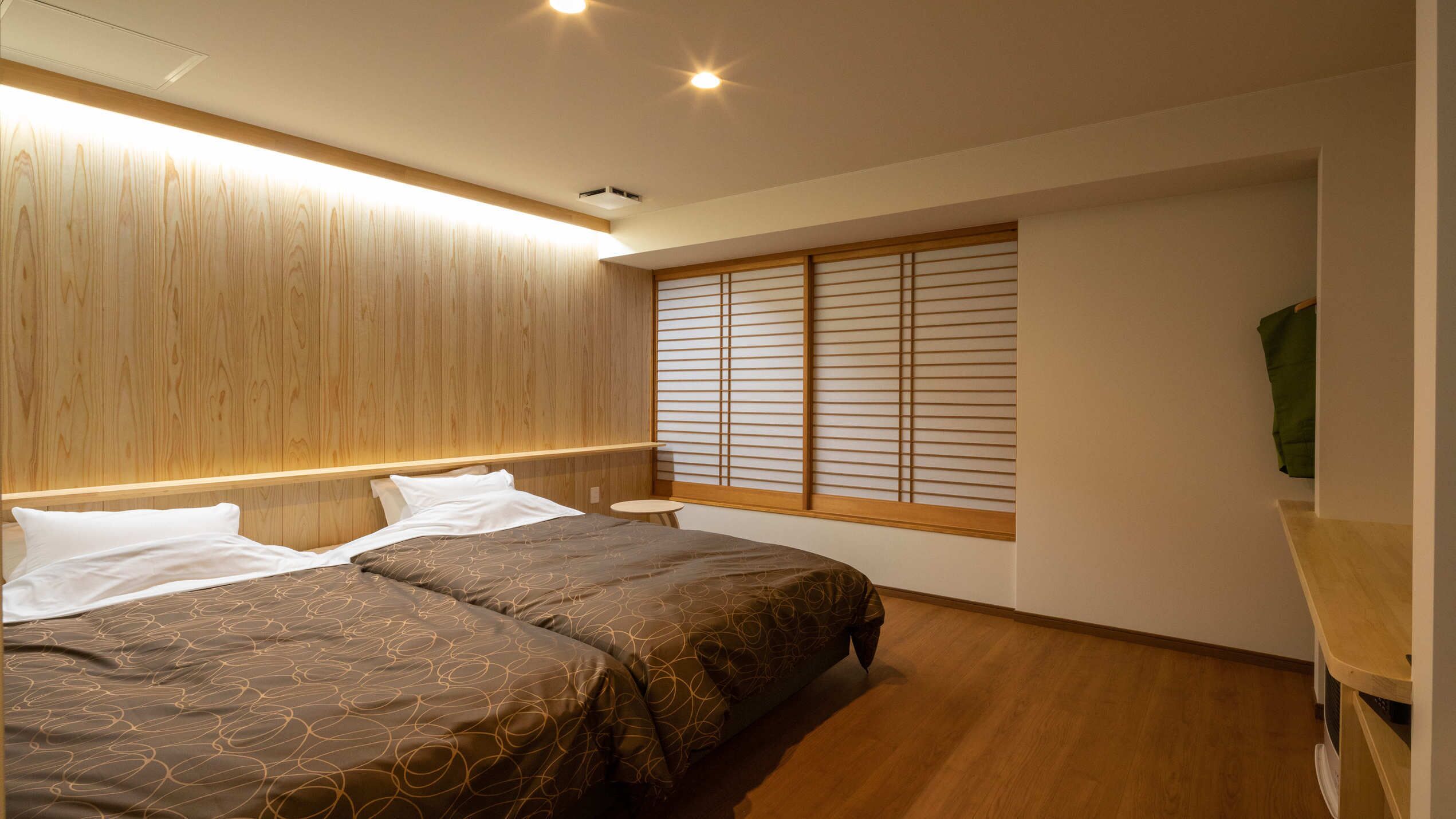 A bedroom with a bed, bedside tables, a window with shoji screens, and a wooden ceiling.