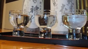 Trois bouteilles de saké et trois petits verres à shooter sur un plateau.