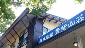Un bâtiment avec une enseigne bleue, de grandes fenêtres et un balcon.