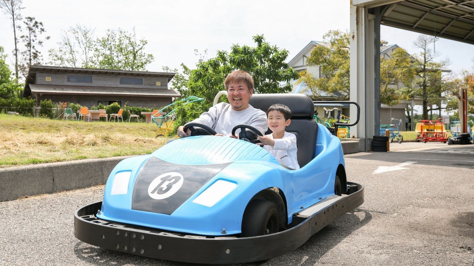 A person driving a blue bumper car with a number 13 on it.