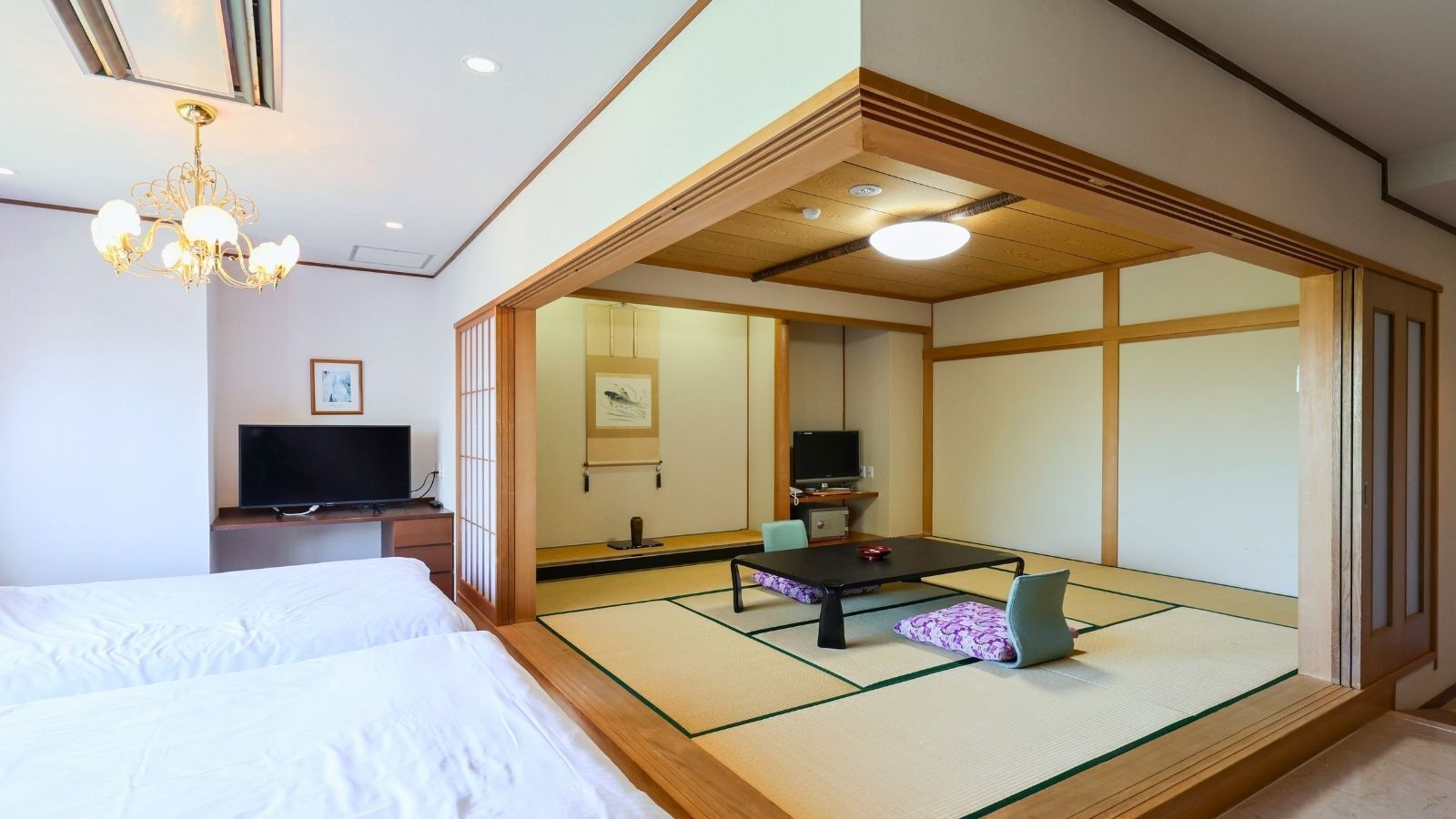 A traditional Japanese room with tatami flooring, a low table, and a television.