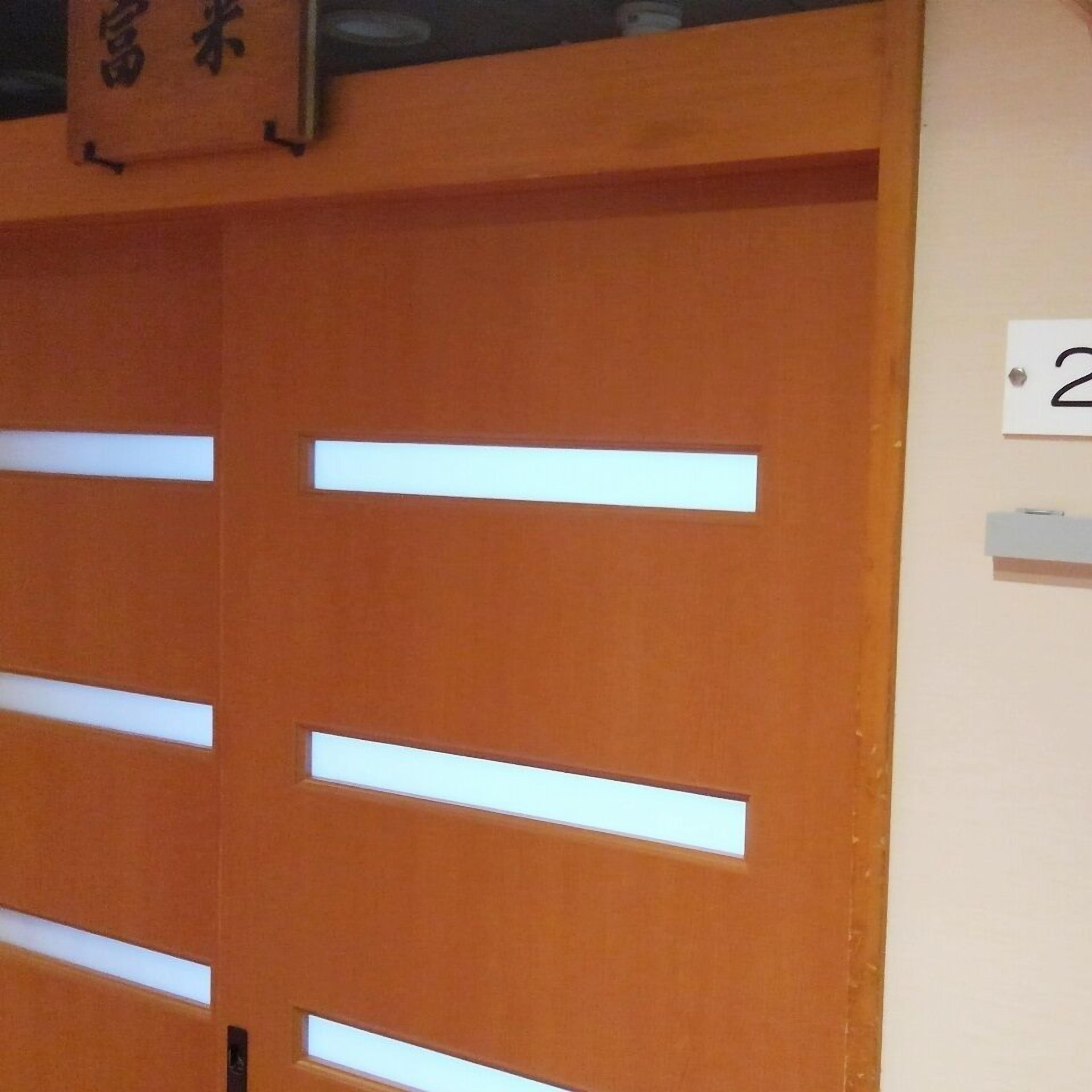 A wooden door with horizontal slats and a white label with the number '2' on the wall to the right.