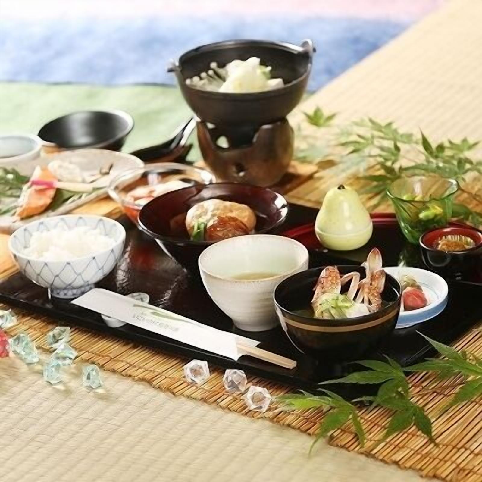 En traditionel japansk måltidspresentation med forskellige retter, herunder sushi, sashimi og en varm gryderet.