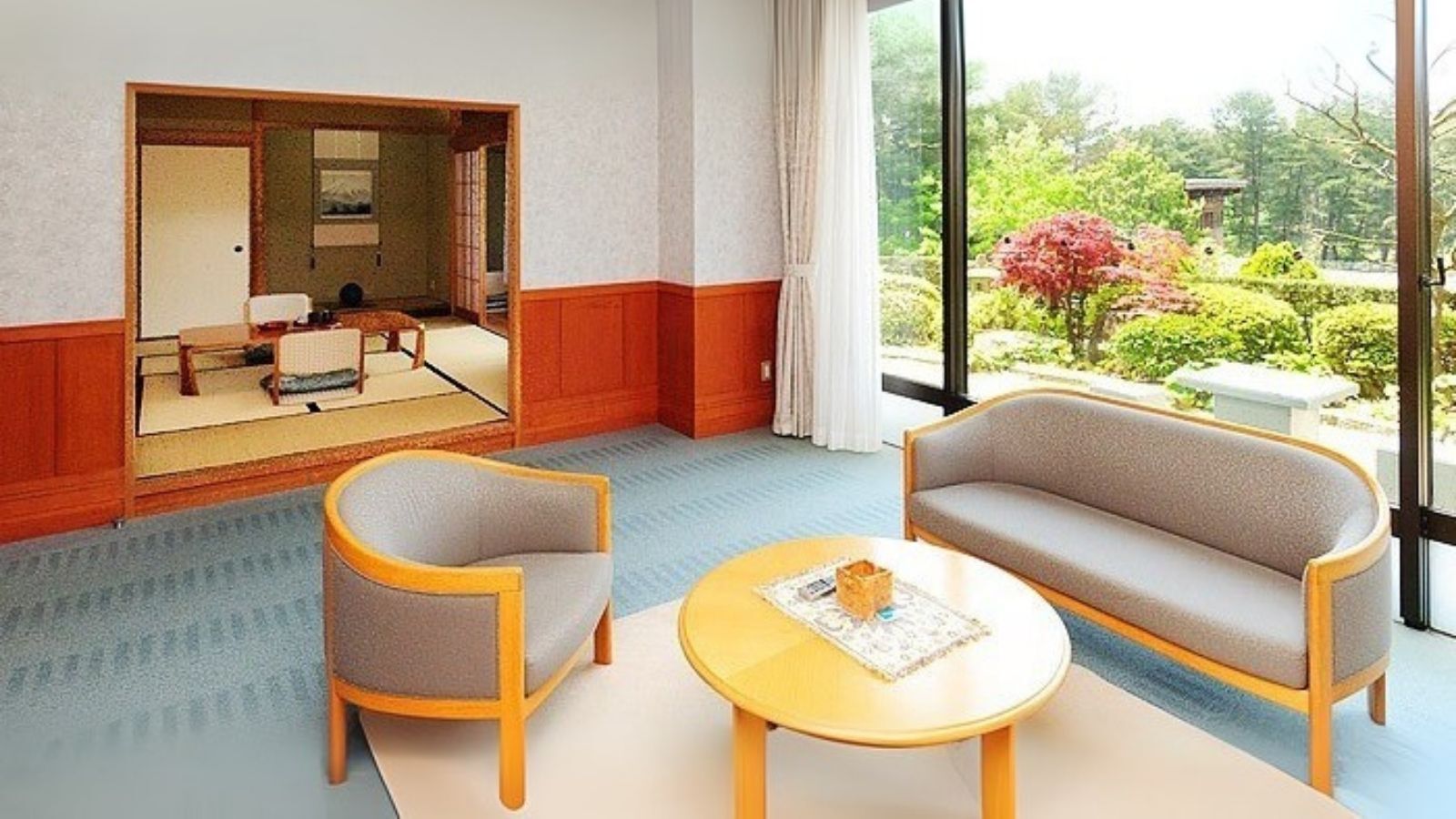 A hotel room with a sofa, chair, and round table.