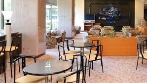 A hotel lobby with round tables, chairs, a sofa area, and a large TV screen. - Shiganosato Onsen Ikoinomura Notohantou (Shika)