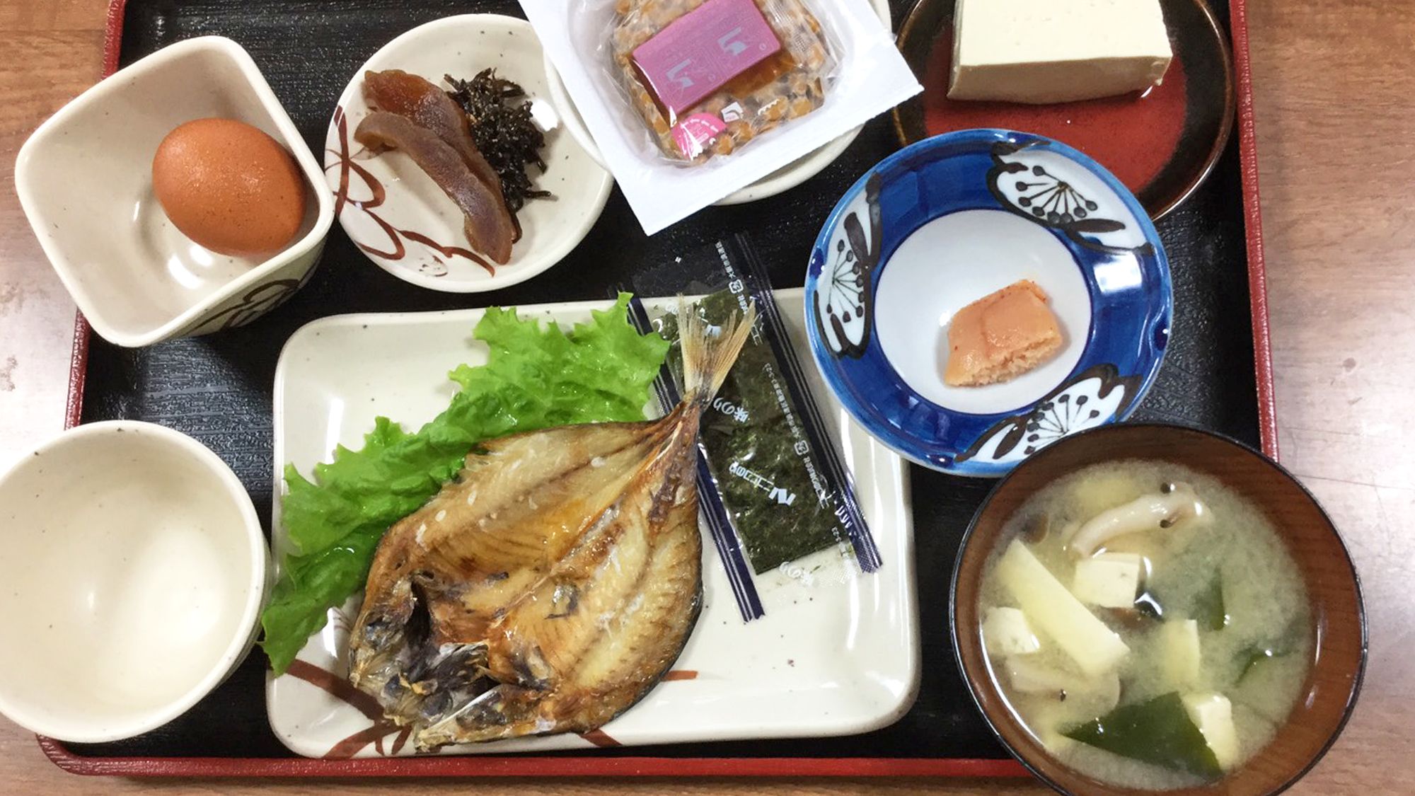 A tray with various Japanese dishes including fish, seaweed, and a bowl of soup.