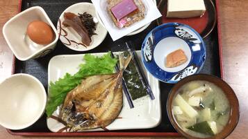 A tray with various Japanese dishes including fish, seaweed, and a bowl of soup.