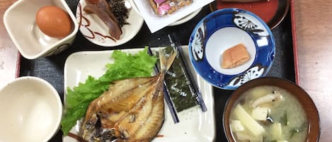 A tray with various Japanese dishes including fish, seaweed, and a bowl of soup.