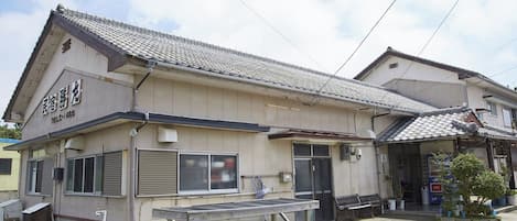 A traditional Japanese building with a tiled roof and a signboard.