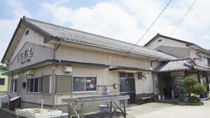 A traditional Japanese building with a tiled roof and a signboard.