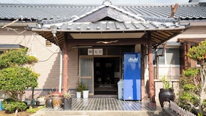 A traditional Japanese building with a tiled roof, a signboard, and a blue refrigerator outside. - Minshuku Katsumaruso <ikinoshima> (Iki)