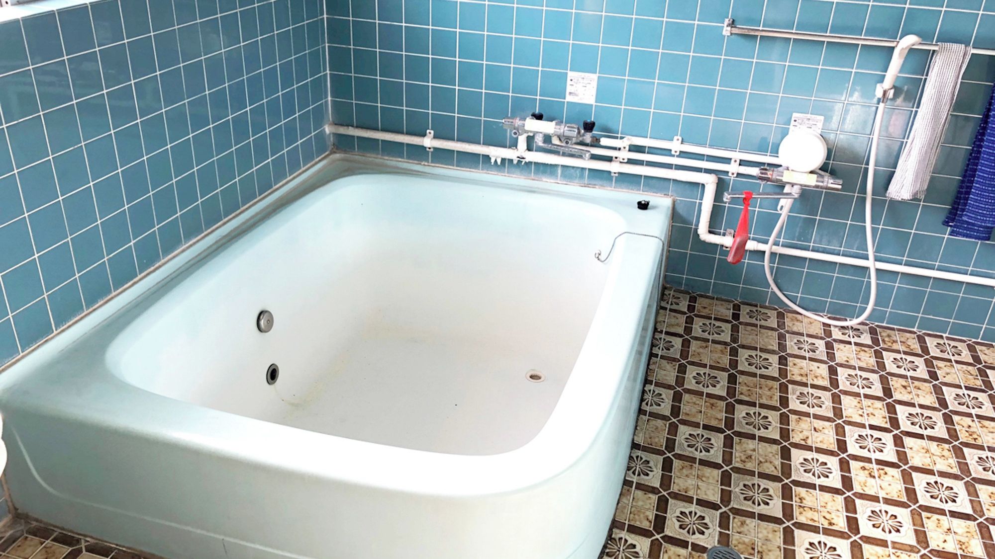 Een badkamer met een bad, een douche en een betegelde vloer.