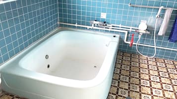 Een badkamer met een bad, een douche en een betegelde vloer.