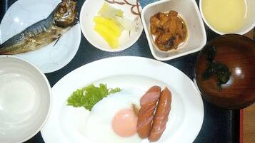A table with various dishes including a plate with sausages and an egg, a bowl of soup, and a fish.