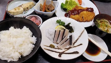 Een dienblad met diverse gerechten, waaronder rijst, sashimi, tempura en een kom soep.