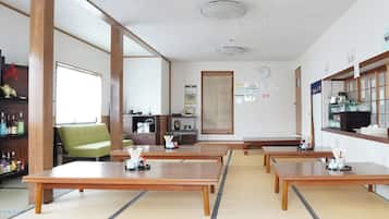 Een traditionele Japanse kamer met tatami vloerbedekking, lage houten tafels en een groene bank.