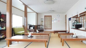 Una habitación tradicional japonesa con suelo de tatami, mesas de madera bajas y un sofá verde.