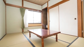 A traditional Japanese room with tatami flooring, a wooden table, a sliding door, and a window with curtains. - Minshuku Katsumaruso <ikinoshima> (Iki)