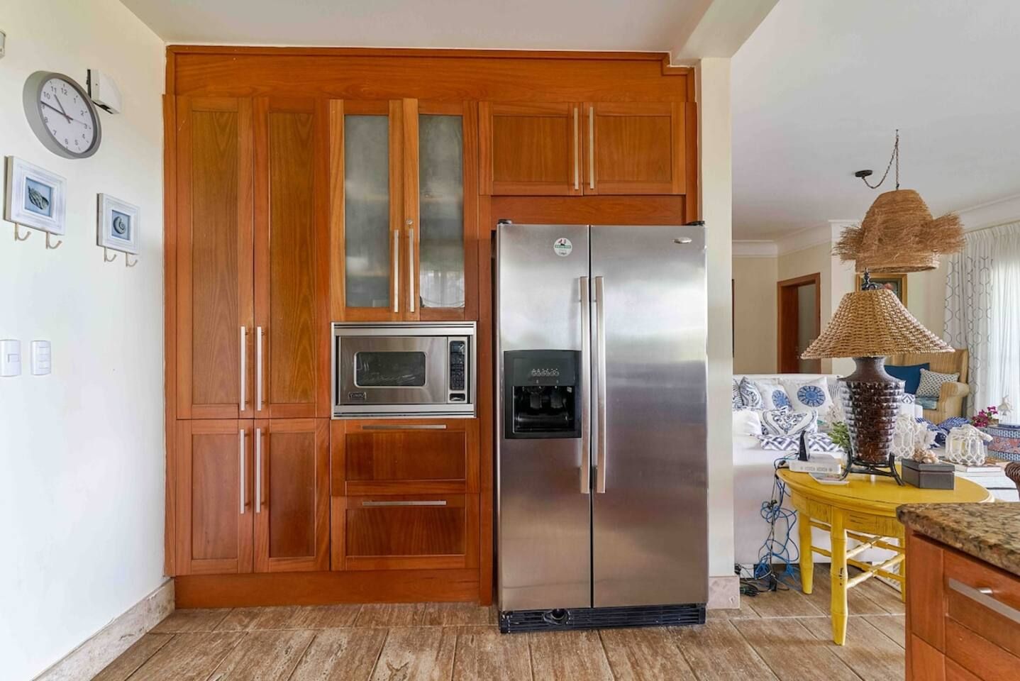 Una cocina con armarios de madera, un refrigerador de acero inoxidable, un microondas y un dispensador de agua.