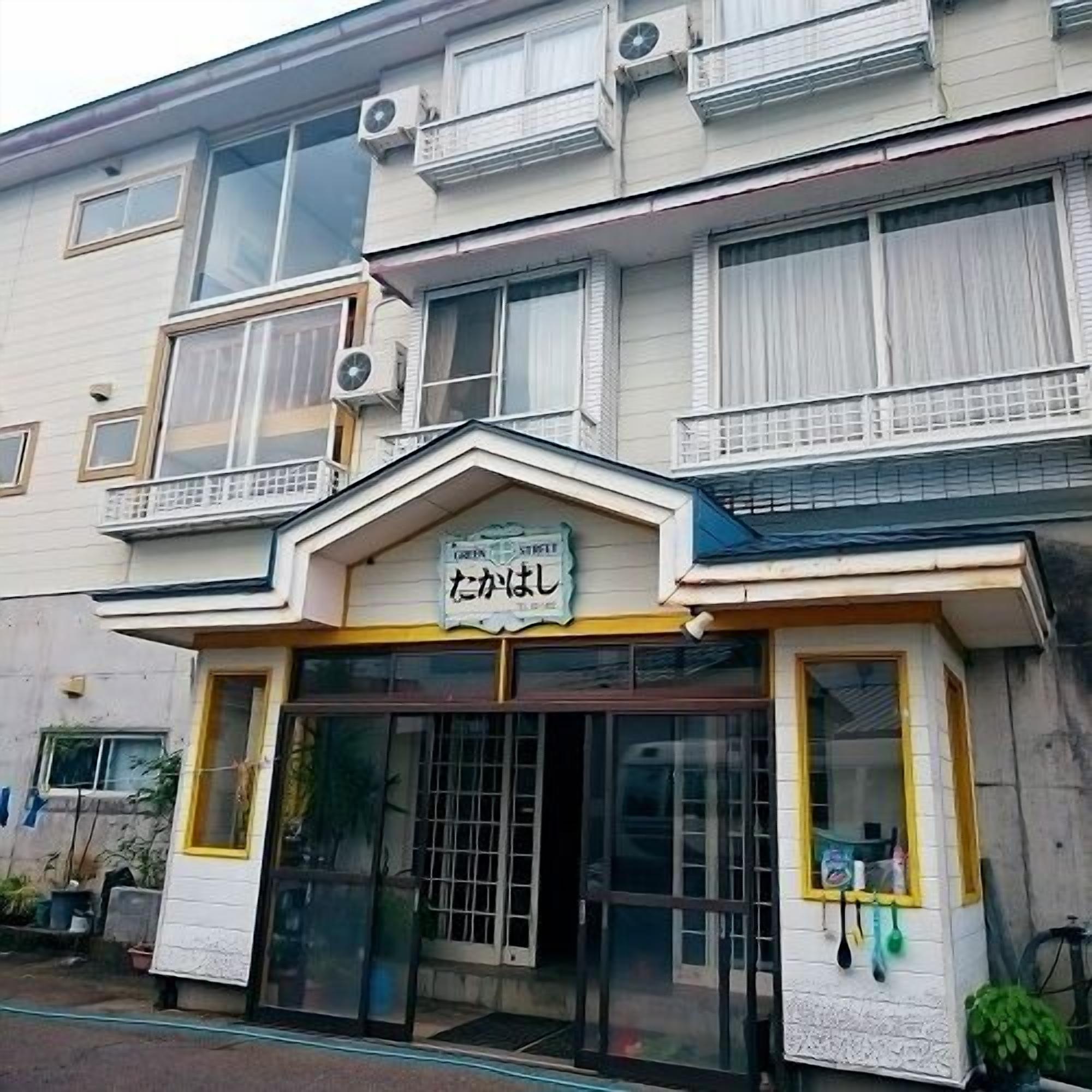 A building with multiple windows, a signboard, and a gated entrance.