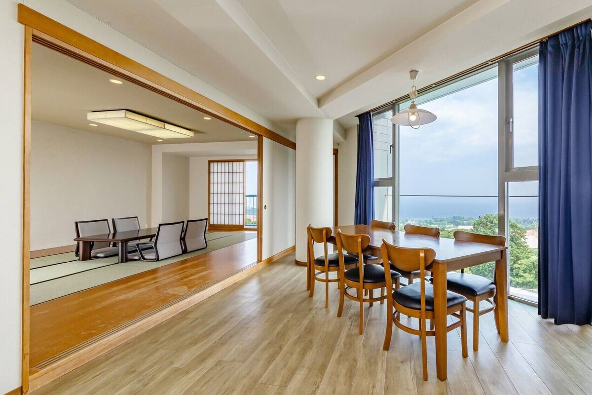 A spacious room with a dining area, large windows, and a view of the outdoors.