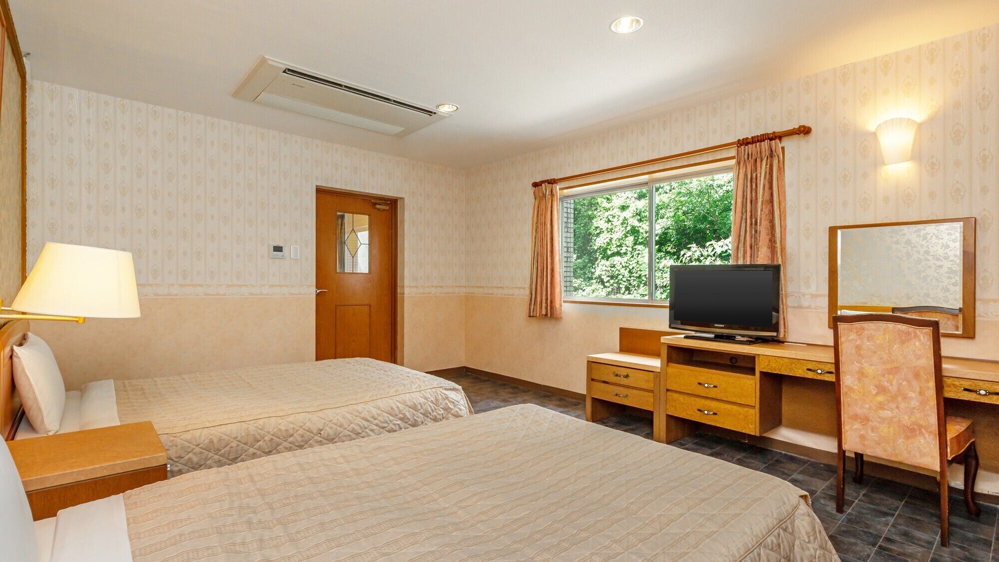 A hotel room with two beds, a desk, a television, a mirror, and a window with curtains.