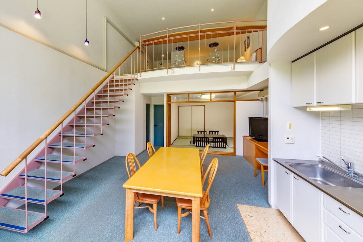 A modern apartment with a dining area, kitchen, and a staircase leading to a loft.