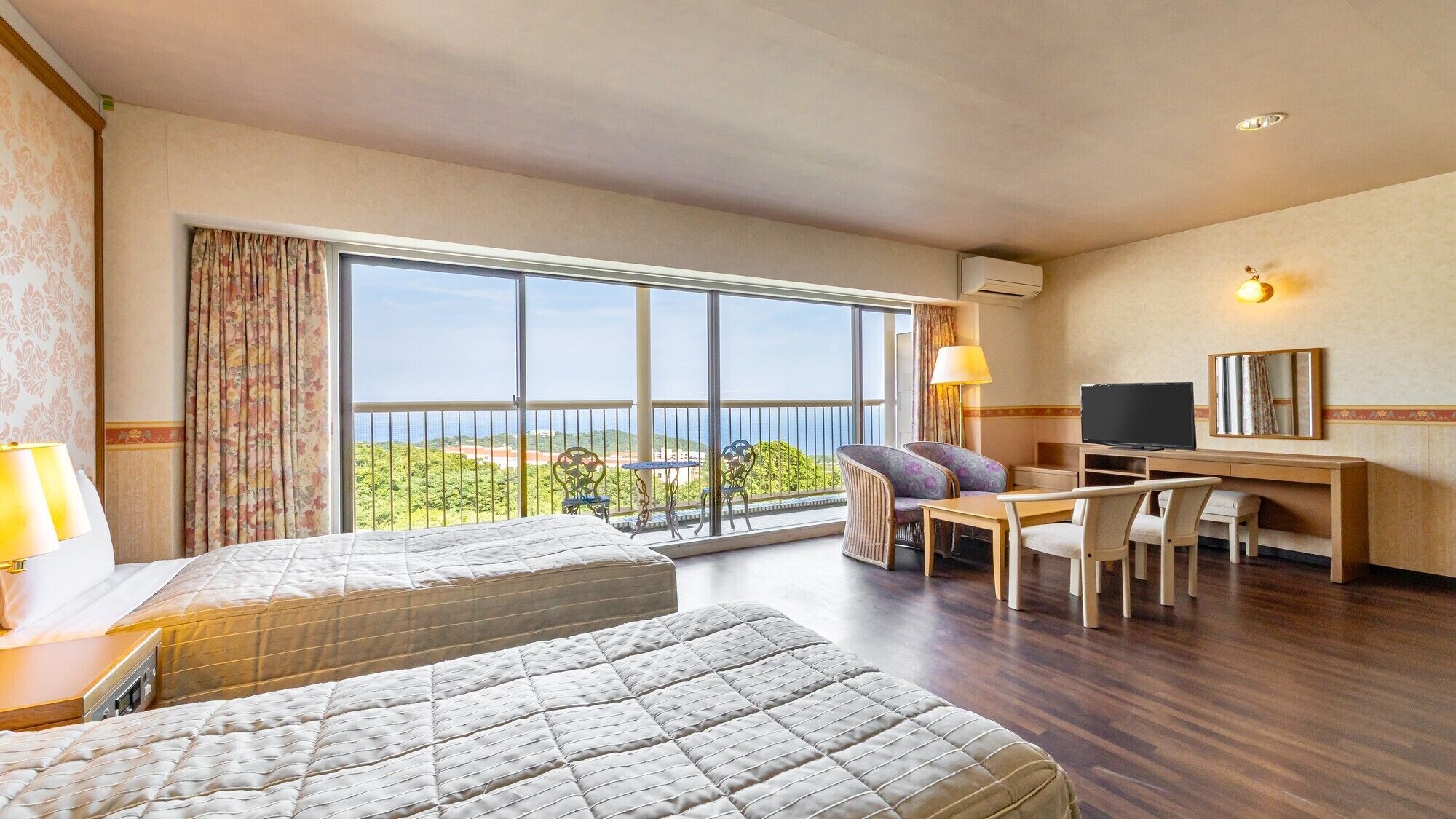 A hotel room with a balcony, a desk with a chair, a bed, and a TV.